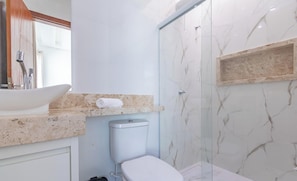 Une salle de bain avec un lavabo, des toilettes et une douche, le tout de couleur blanche.