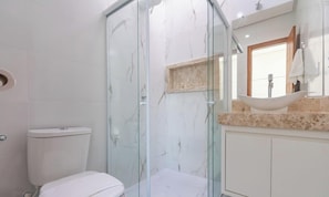 Une salle de bain avec une douche à parois de verre, des toilettes et un lavabo doté d’un plan-vasque en marbre.
