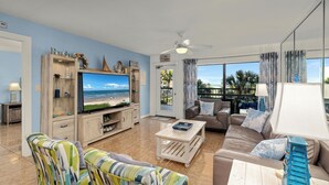 A living room with a television, sofas, a coffee table, and a view of the beach. - Steps to Pool & Beach: South Padre Island Retreat! (South Padre Island)