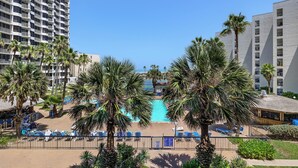 A hotel with a pool surrounded by palm trees and a beach area with lounge chairs. - Steps to Pool & Beach: South Padre Island Retreat! (South Padre Island)
