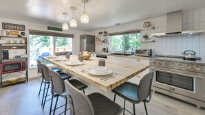 Una cocina moderna con una isla central, taburetes de bar, microondas, estufa y espacio para café.