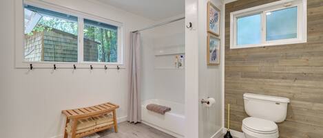 Een badkamer met douche, toilet, bankje en houten wandbekleding.