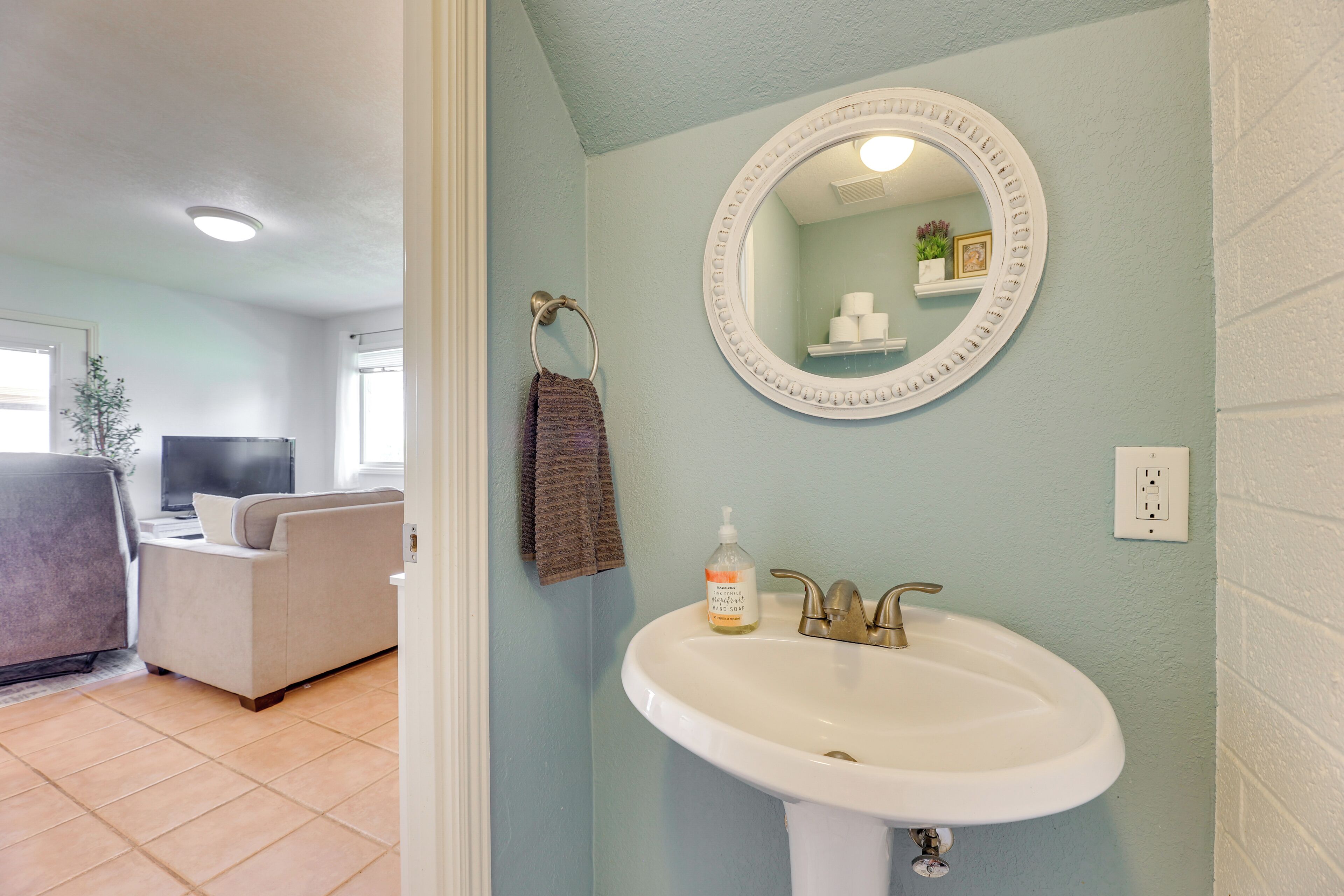 A bathroom with a white sink, a round mirror, and a towel rack.