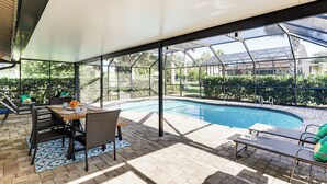 Ett takförsett utomhusområde med en pool, sittplatser och utsikt över den omgivande vegetationen.