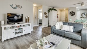 A modern living room with a grey sofa, white entertainment unit, and a flat-screen TV. - Renovated Villa Btwn Lake Sumter & Spanish Springs (Lady Lake)
