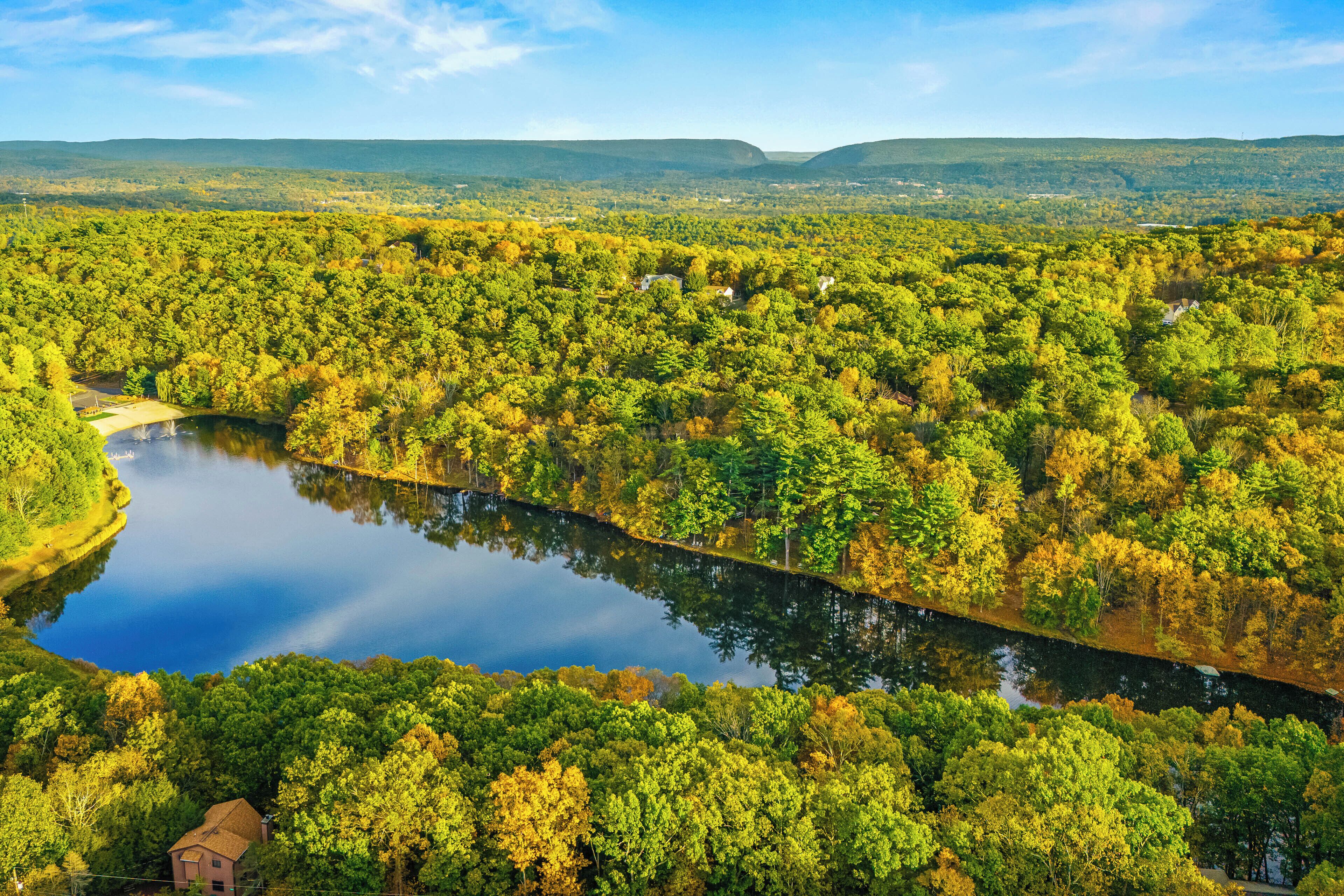 A river winding through a densely forested area with a small building near the water's edge.