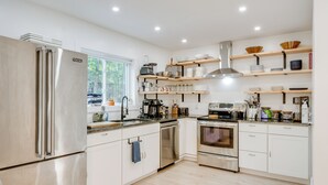 A modern kitchen with stainless steel appliances, wooden shelves, and a view of the outdoors. - Private Yard, Playset: Family Home in Penn Estates (East Stroudsburg)