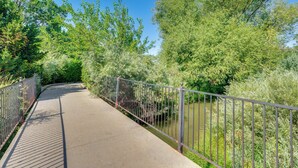 A concrete pathway with metal railings, surrounded by lush greenery and trees.