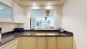 Una cocina moderna con encimeras de granito, horno empotrado y vista al comedor.