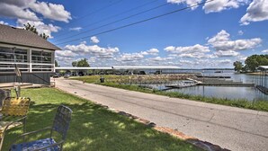 A lakeside view with a dock, a building with large windows, and outdoor seating. - Poolside Bliss & Lake Fun: Monkey Island Retreat! (Afton)