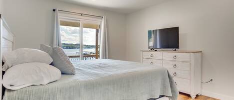 A bedroom with a bed, a dresser, a television, and a window with a view.