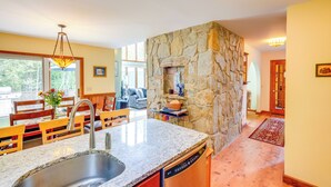 A kitchen with a stone wall, granite countertop, and a dishwasher.