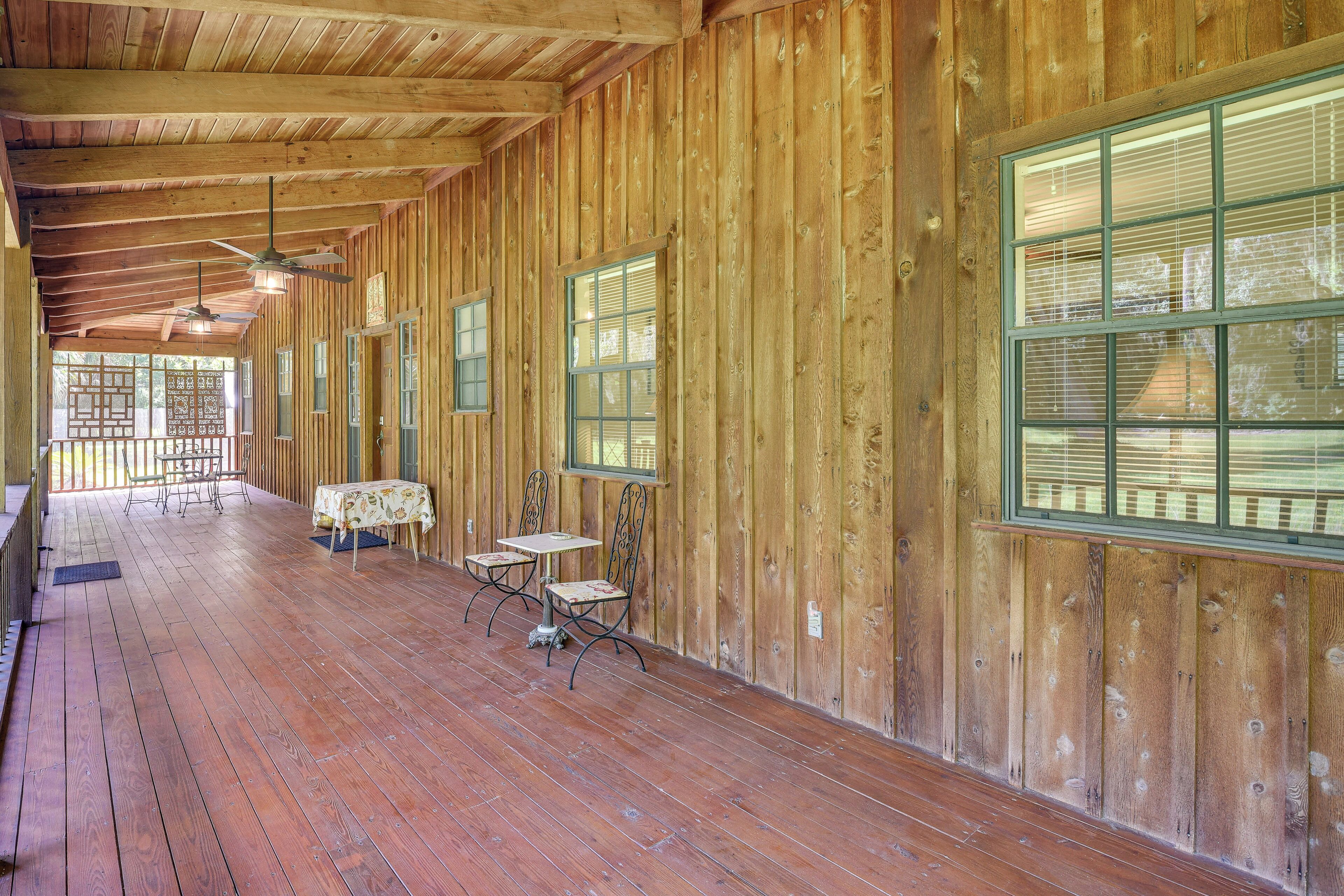 Un intérieur spacieux en bois, avec un long couloir, de grandes fenêtres et un ventilateur de plafond.