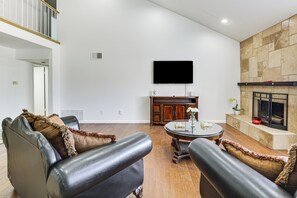 A living room with leather sofas, a flat-screen TV, a fireplace, and a dining table. - Spacious Getaway w/ Pool in La Mesa! (La Mesa)