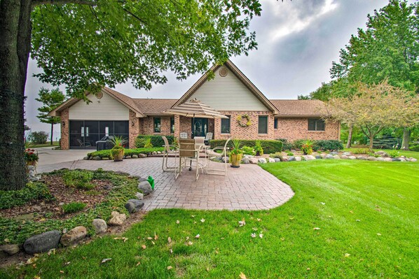 A two-story house with a brick exterior, a front porch with a table and chairs, and a well-maintained lawn. - Large Family Home w/ Deck & Yard on Lake Huron (Deckerville)