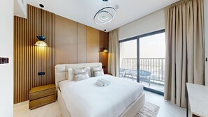 Camera d'albergo moderna con un letto grande, parete rivestita in legno, due lampade a sospensione, un balcone con vista e una piccola scrivania.