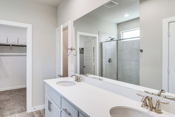 A modern bathroom with a double sink vanity, a large mirror, and a walk-in shower. - Spacious Family Home w/ Office in Midland-odessa! (Midland)