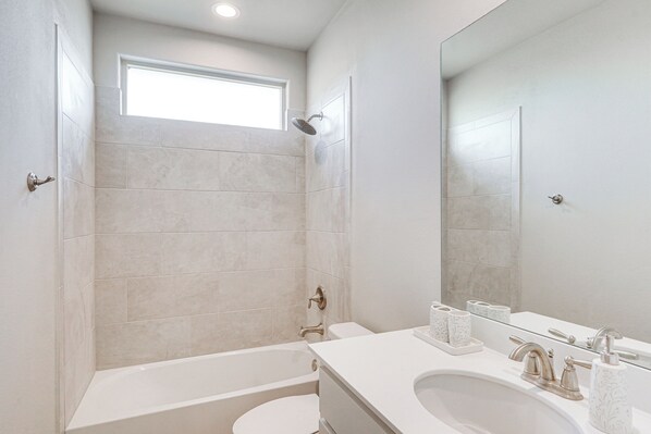 A modern bathroom with a bathtub, toilet, and sink. - Spacious Family Home w/ Office in Midland-odessa! (Midland)