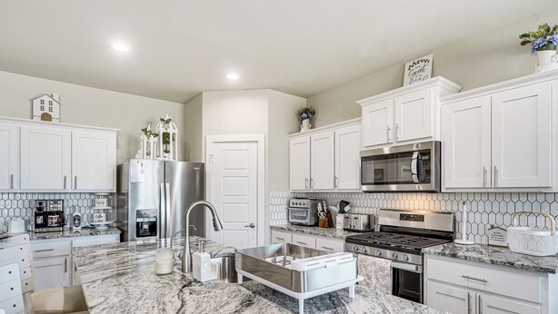 A modern kitchen with white cabinets, a granite countertop, stainless steel appliances, and a farmhouse sink. - Spacious Family Home w/ Office in Midland-odessa! (Midland)
