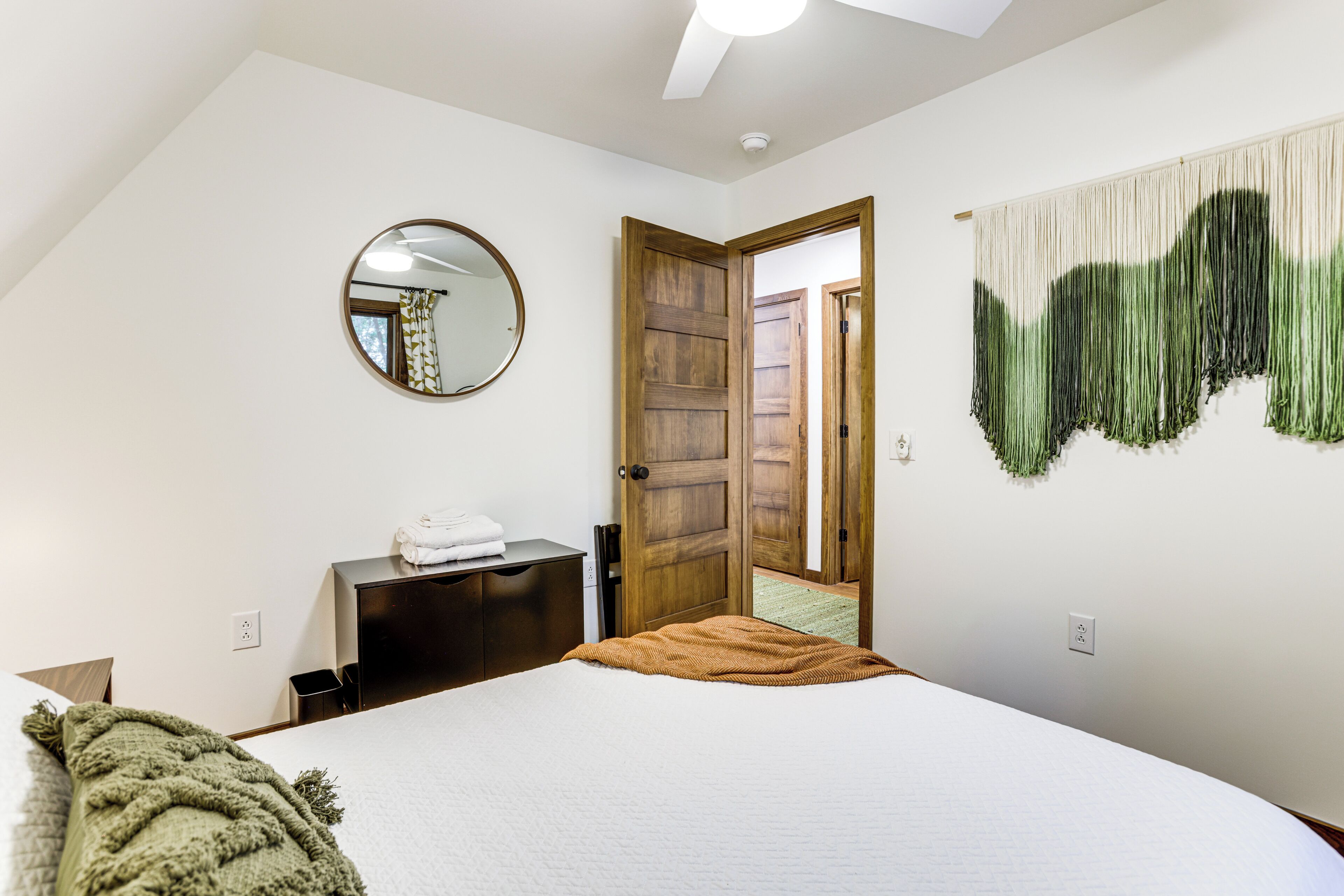 A bedroom with a bed, a dresser, a mirror, and a door leading to another room.