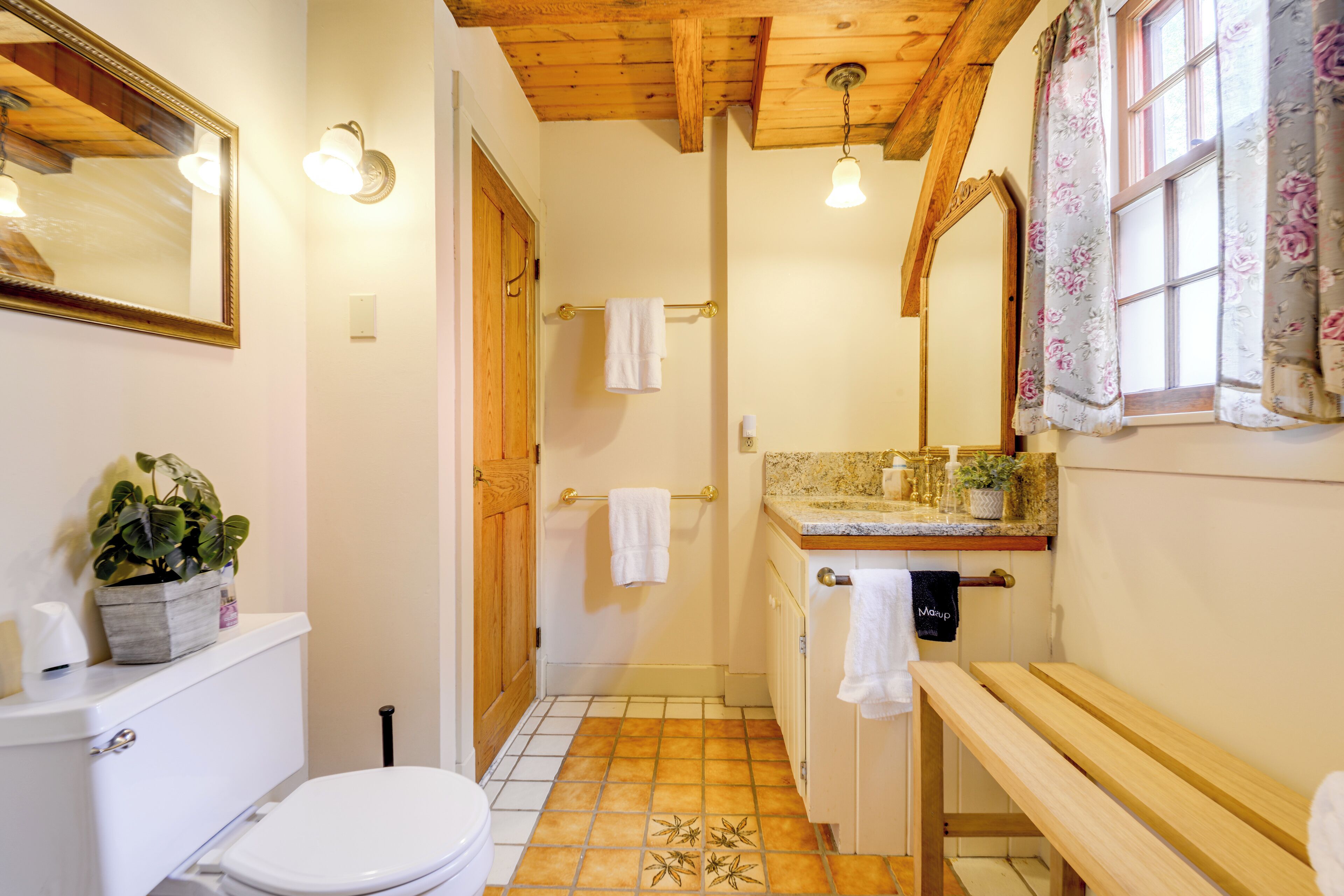 Ein Badezimmer mit Toilette, Waschbecken, Sitzbank und Spiegel.