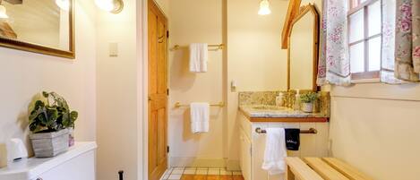 Ein Badezimmer mit Toilette, Waschbecken, Sitzbank und Spiegel.