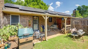 A backyard with a covered patio, a barbecue grill, and a swing chair.