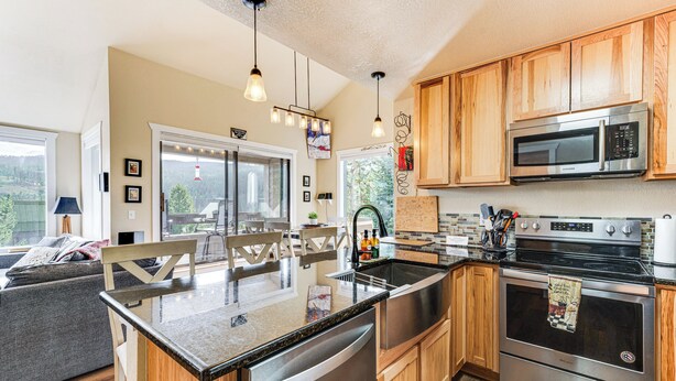 A modern kitchen with wooden cabinets, stainless steel appliances, and a large island with a sink.