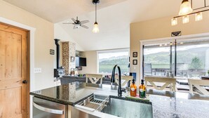 A modern kitchen with a stainless steel sink, a built-in oven, and a large window overlooking a scenic landscape.
