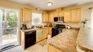A kitchen with wooden cabinets, a microwave, stove, dishwasher, and a large window.