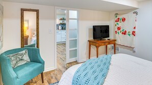 A bedroom with a bed, a television on a wooden table, a teal armchair, and a wardrobe. - 6 Mi to Cpkc Stadium: Convenient Kansas City Apt (Riverside)
