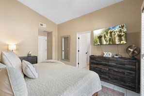 A bedroom with a bed, dresser, TV, and a wall-mounted fan. - Heated Pool & Spa: Catalina Mtn-view Home! (Oro Valley)