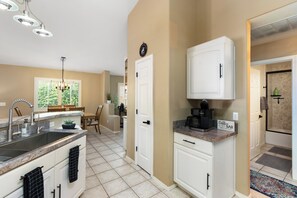A modern kitchen with a built-in coffee station, a dining area with a bench, and a view of the outdoors. - Heated Pool & Spa: Catalina Mtn-view Home! (Oro Valley)