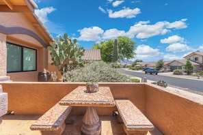 A patio with a table and chairs, surrounded by cacti and desert plants. - Heated Pool & Spa: Catalina Mtn-view Home! (Oro Valley)