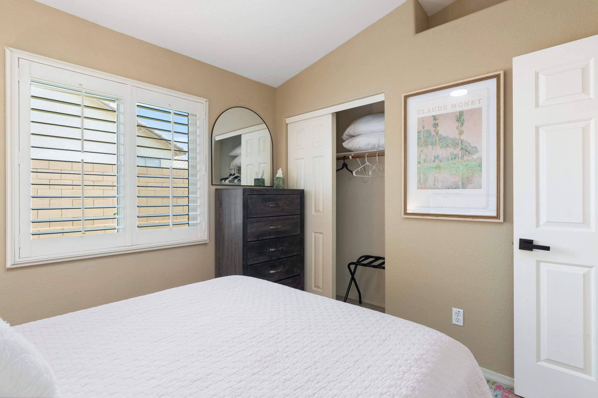 A bedroom with a bed, dresser, mirror, and a door.