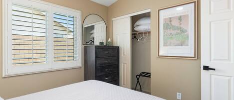A bedroom with a bed, dresser, mirror, and a door.