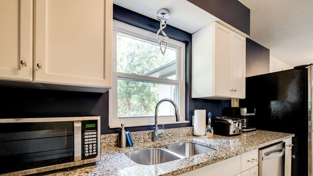 A kitchen with white cabinets, a granite countertop, a stainless steel sink, a microwave, a toaster, and a dishwasher. - Tree-lined Retreat 4 Mi to Three Sisters Springs! (Crystal River)