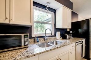 A kitchen with white cabinets, a granite countertop, a stainless steel sink, a microwave, a toaster, and a dishwasher. - Tree-lined Retreat 4 Mi to Three Sisters Springs! (Crystal River)