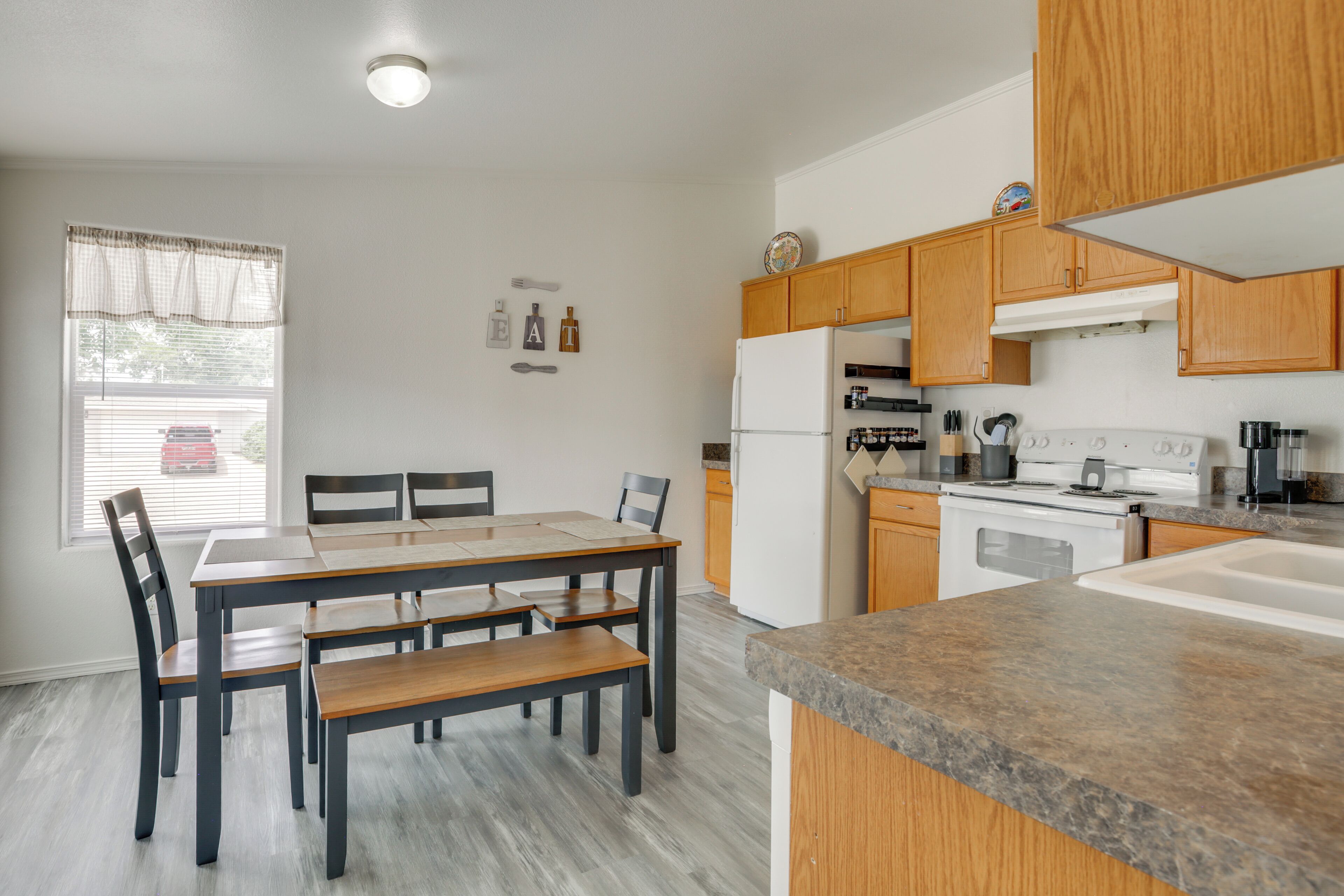 Une cuisine moderne avec des meubles en bois, un réfrigérateur blanc, une cuisinière et un coin repas comprenant une table et des chaises.