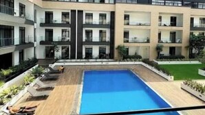 A modern building with a central swimming pool, multiple balconies, and outdoor seating areas. - premier luxury apartment (Accra)