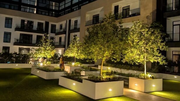 A modern building with multiple balconies and a well-lit courtyard with trees and planters. - premier luxury apartment (Accra)