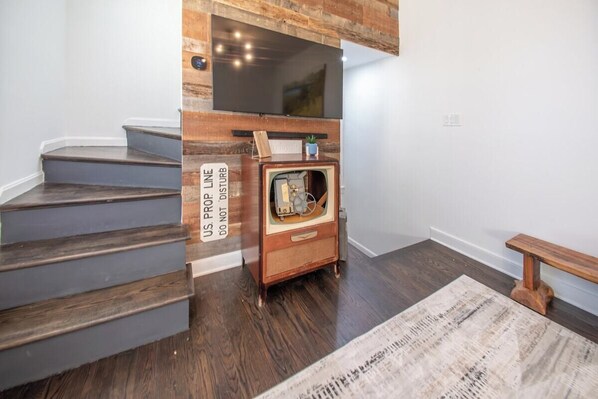 A staircase with dark wood steps and a wall-mounted television. - Fells Point Charm with a View (Baltimore)