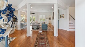 A spacious living area with hardwood floors, a chandelier, and a view to the dining area. - Hydrangea House in Gated Compass Point, sleeps 12 with a pool (St Simons Island)