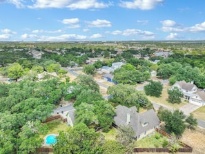 A residential area with houses, trees, and a swimming pool. - Charming Kyle Retreat with Pool, Porch & Walk to Downtown (Kyle)