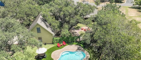 Un quartier résidentiel avec une piscine, une pelouse et une petite maison.