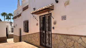 Un edificio con patio empedrado, entrada protegida por una reja y un letrero que dice "CASA LISTA".