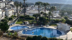 Zona residencial con una piscina grande rodeada de palmeras y casas.