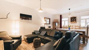 A modern living room with a sectional sofa, a dining table, and a kitchen area. - Very large modern apartment for 8 people (Königstein)