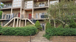 A multi-story residential building with a stone facade, multiple balconies, and a central staircase leading to the entrance. - Hilltop 3BR for 10, Private Garage, Skyline Views (Covington)