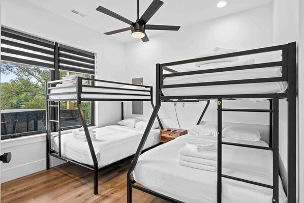 Una habitación con literas, ventilador de techo y ventana con persianas.